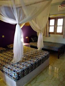 a bedroom with a bed with mosquito nets on it at Le Chamama in Niaga