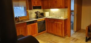 una cucina con armadi in legno, lavandino e forno a microonde di Le Passage a Salvan