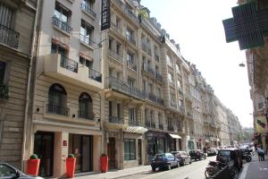 um edifício alto com carros estacionados numa rua da cidade em Westside Arc de Triomphe Hotel em Paris