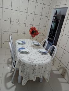 ein weißer Tisch mit einer Vase Blumen drauf in der Unterkunft Casa Morumbi Foz do Iguaçu in Foz do Iguaçu
