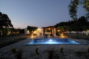 a pool in the middle of a yard at night at Elia suites in Ialysos