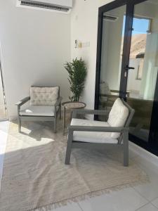uma sala de estar com duas cadeiras e uma mesa em Home X4 em Al Wāşil