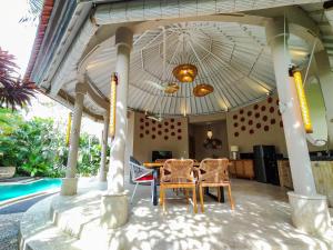 een patio met een tafel en stoelen en een zwembad bij Seminyak Square Hotel And Villas in Seminyak