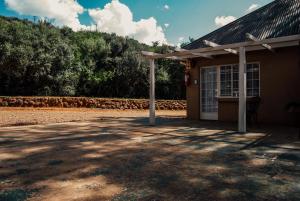 ein kleines Gebäude mit einer Veranda und einem Baum in der Unterkunft Farm stay at Fennel Cottage on Haldon Estate in Bloemfontein