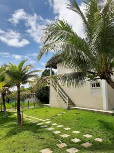 una casa blanca con palmeras delante en Pousada Cantoria en Cumuruxatiba