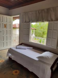 a bedroom with a large bed with a window at Pousada Cantoria in Cumuruxatiba