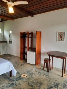 a room with a bed and a table and a desk at Pousada Cantoria in Cumuruxatiba