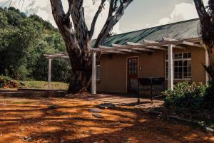 una casa con un árbol delante de ella en Farm stay at Rosemary Cottage on Haldon Estate en Bloemfontein