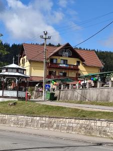 una casa amarilla con un cenador frente a ella en Edelweis Floare de Colt, en Borsec