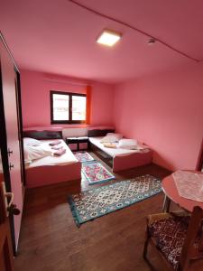 a pink room with two beds and a table at Edelweis Floare de Colt in Borsec