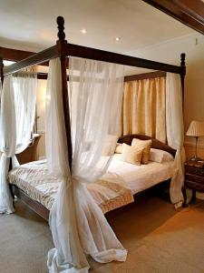 a bedroom with a canopy bed with white curtains at The Crown House Inn in Great Chesterford