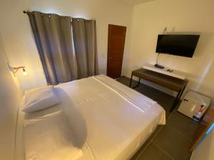 1 dormitorio con 1 cama y escritorio con TV en Pousada Suzimar, en Fernando de Noronha