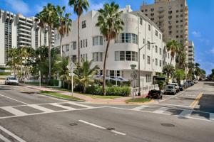 an empty street with a white building and palm trees at Hotel Trouvail Miami Beach in Miami Beach