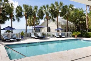 a swimming pool with chairs and palm trees at The Cottages on Charleston Harbor in Charleston