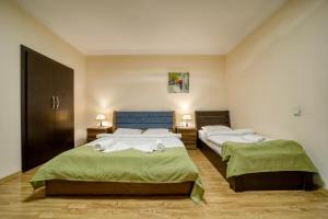 a bedroom with two beds with green sheets and a blue headboard at Nine Hotel in Tbilisi City
