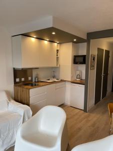 een keuken met witte kasten en een witte stoel in een kamer bij Appartement avec terrasse in Les Deux Alpes