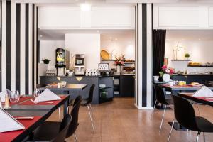 ジュエ・レ・トゥールにあるMercure Tours Sudのテーブルと椅子のあるレストラン、キッチンが備わります。