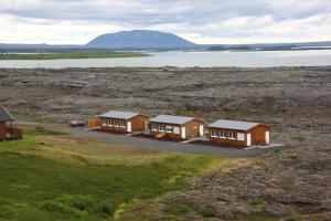 a row of houses in a field next to a body of water at Hlid Bed and Breakfast in Myvatn