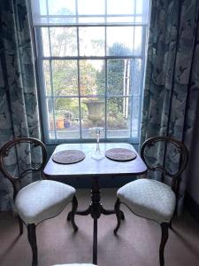 uma mesa e duas cadeiras em frente a uma janela em Luxury flat in Totnes em Totnes