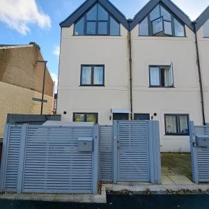 a white house with blue gates in front of it at Lovely and Modern Groundfloor 1 Single Bedroom Condo with Netflix, Tea/Coffee/Biscuits in Bristol