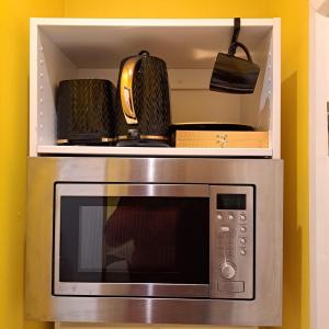 a microwave with two pans on top of it at Lovely and Modern Groundfloor 1 Single Bedroom Condo with Netflix, Tea/Coffee/Biscuits in Bristol