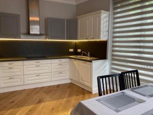 a kitchen with white cabinets and a sink and a table at Belle Maison de 5 pièces (150 m²) in Sceaux
