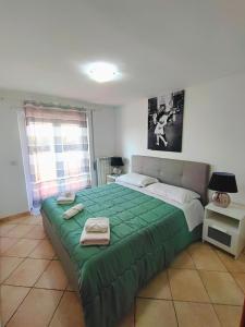 una camera da letto con un grande letto verde con asciugamani di Attico Sea and Sunset a Lido di Ostia