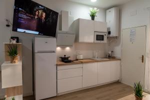 uma cozinha com armários brancos e uma televisão de ecrã plano em Vivienda Turística Playa El Portil em El Portil