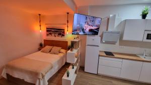 Habitación pequeña con cama y TV en la pared. en Vivienda Turística Playa El Portil, en El Portil
