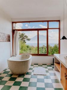 a bathroom with a tub and a large window at Designers Luxury Retreat with breathtaking gardens in Tzununá