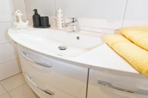 a bathroom with a white sink and a yellow towel at Frauenpreiß Ferienwohnungen in Cuxhaven