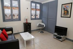 a living room with a couch and a tv at Appartement du Port de Honfleur in Honfleur