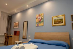 ein Schlafzimmer mit einem blauen Bett und Gemälden an der Wand in der Unterkunft Vico 11 in Gaeta