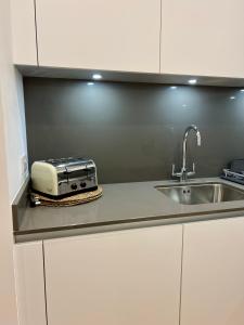 a kitchen counter with a toaster and a sink at Cosy, modern 1-bed apartment in Bath's iconic centre in Bath