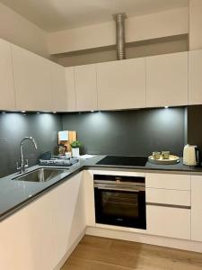 a kitchen with white cabinets and a sink at Cosy, modern 1-bed apartment in Bath's iconic centre in Bath