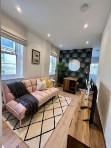 a living room with a pink couch and a tv at Cosy, modern 1-bed apartment in Bath's iconic centre in Bath