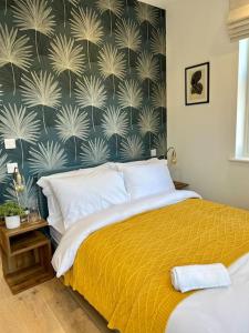 een slaapkamer met een bed met een geel dekbed en een muur bij Cosy, modern 1-bed apartment in Bath's iconic centre in Bath