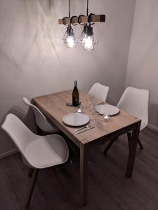 uma mesa de madeira com cadeiras brancas e uma garrafa de vinho em Harzbude em Braunlage