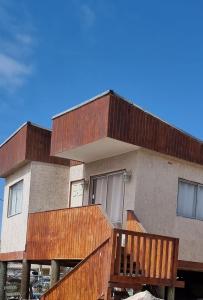 a house with wooden decks and a blue sky at Cabañas Aquila D'Arroscia in Bahia Inglesa