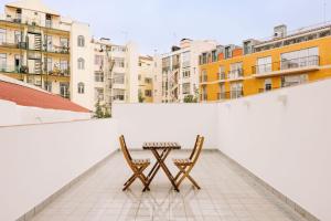 un tavolo e due sedie su un balcone con edifici di City Stays São Lázaro Apartments a Lisbona