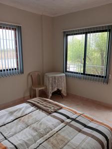 1 dormitorio con cama, mesa y ventanas en Cómo en casa, en Tarija