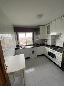 a kitchen with white appliances and a window at Bonito apartamento en la playa in Sanxenxo +9 photos