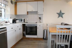 a kitchen with white cabinets and a table with a microwave at Lobster Pot - Mount Brioni in Downderry +6 photos