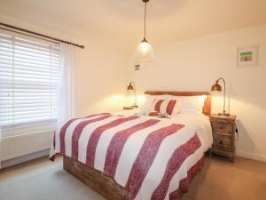 a bedroom with a bed with a striped comforter and a window at 4 East Green, Southwold in Southwold