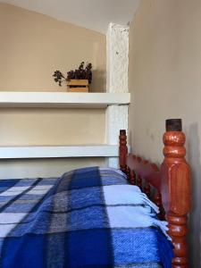 a bedroom with a bed with a blue plaid blanket at Casa Qatzij - Guest House, Lake Atitlan in San Lucas Tolimán