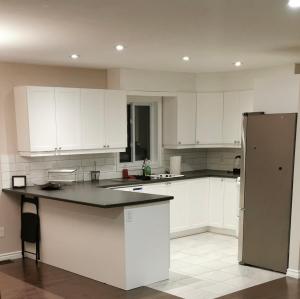 a kitchen with white cabinets and a refrigerator at Beautiful 3 bedroom house in Ottawa