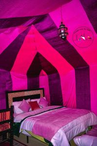 a bedroom with a pink tent with a bed at Overnight Camp Erg Chebbi in Merzouga