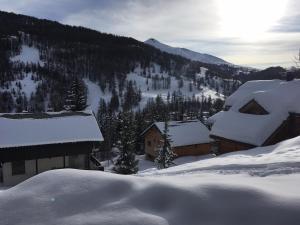 un pueblo cubierto de nieve con montañas en el fondo en Home Vars. Le studio, en Vars