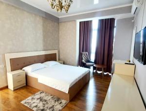 een slaapkamer met een bed, een stoel en een televisie bij LAMIYA Aparts Hotel in Alma-Ata
