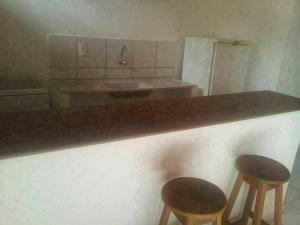 una cocina con 2 taburetes y una barra con fregadero en Hostel Margo en Natal